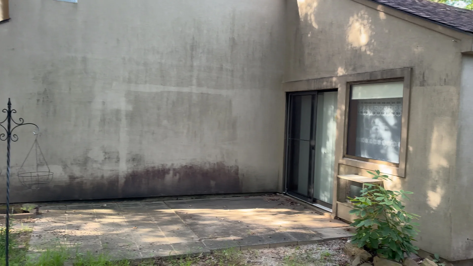 Stucco back patio wall in Fairfield Bay Arkansas before soft washing, with heavy mold and algae staining