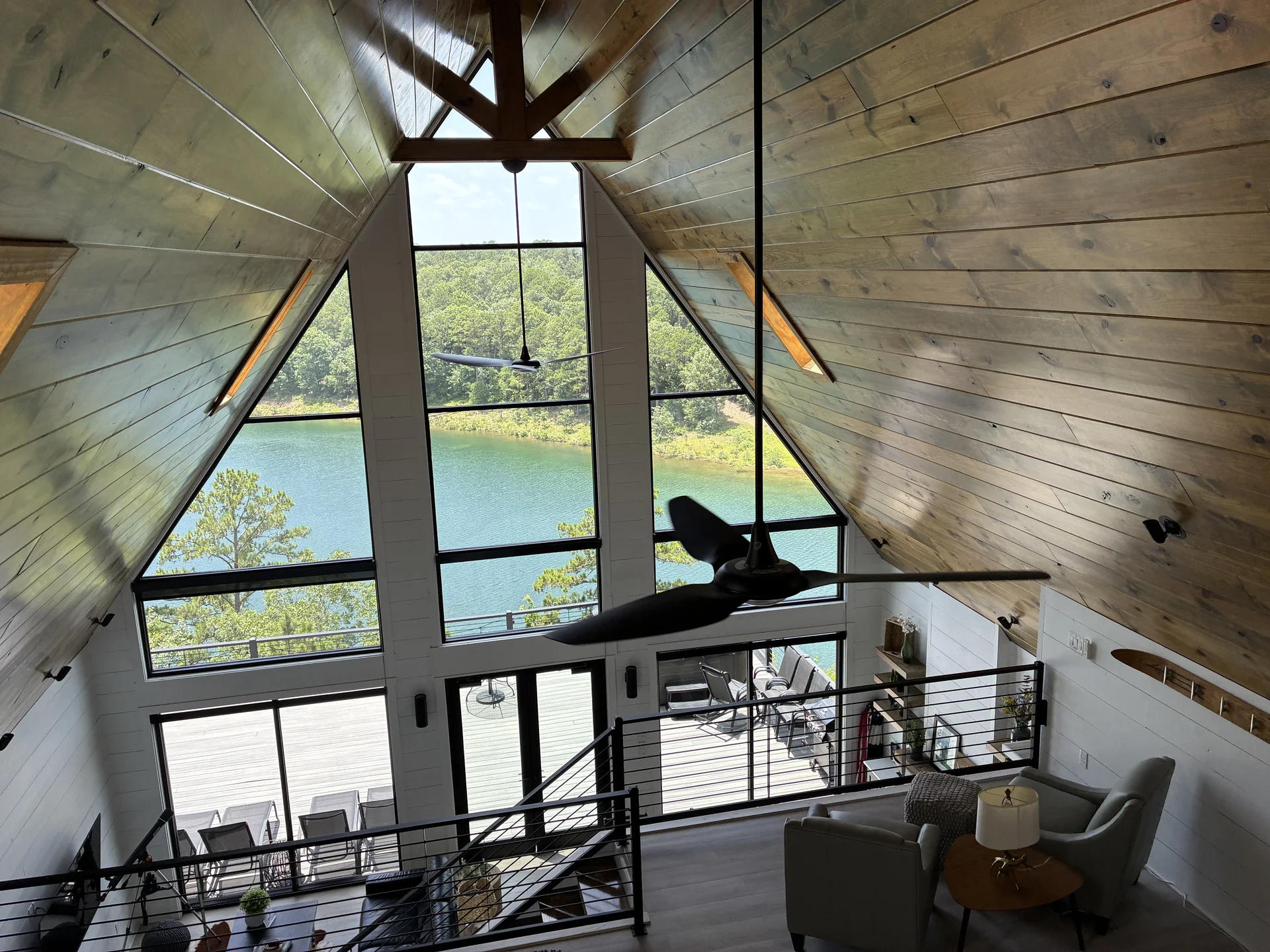 Greers Ferry Lake seen through the cleaned two-story window wall of an A-frame vacation rental in Drasco Arkansas