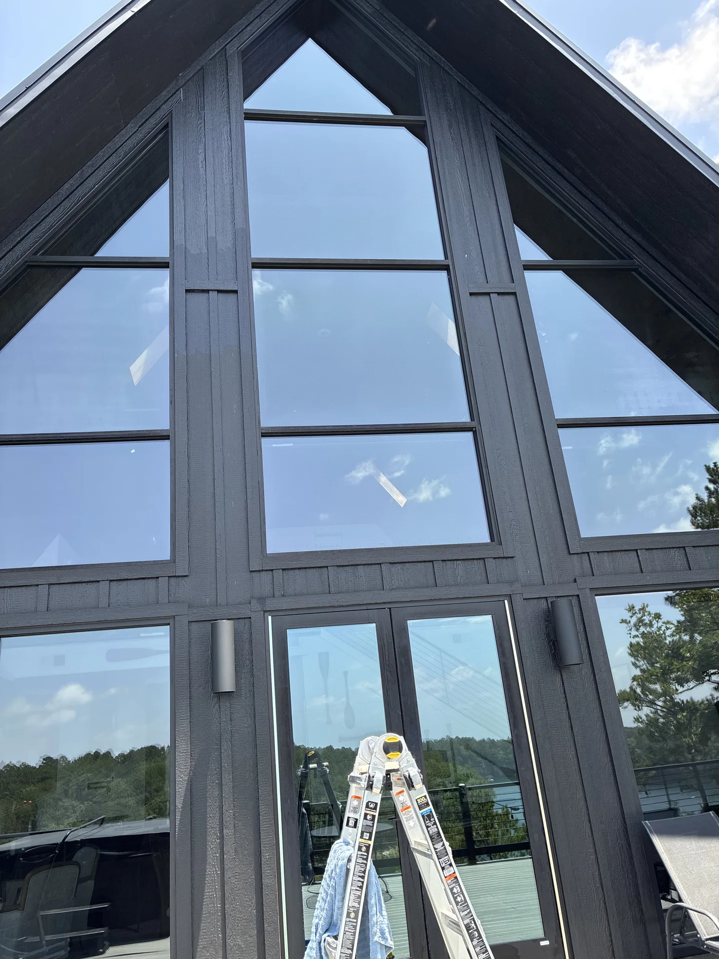 Two-story lakeside window wall on a Drasco Arkansas A-frame rental during window cleaning